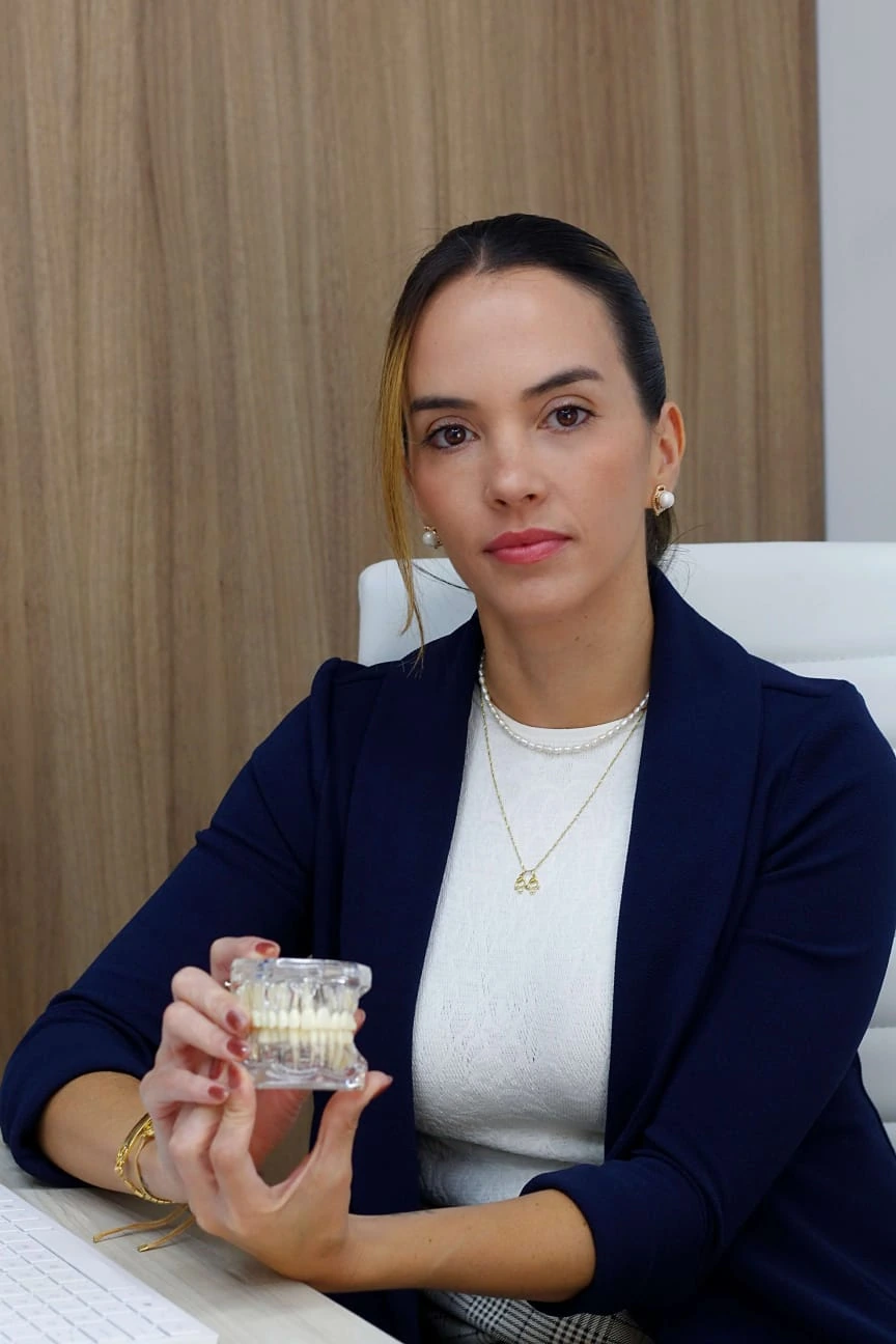 Dra. Andrea Rocha de blazer azul-marinho, segurando um modelo de arcada dentária